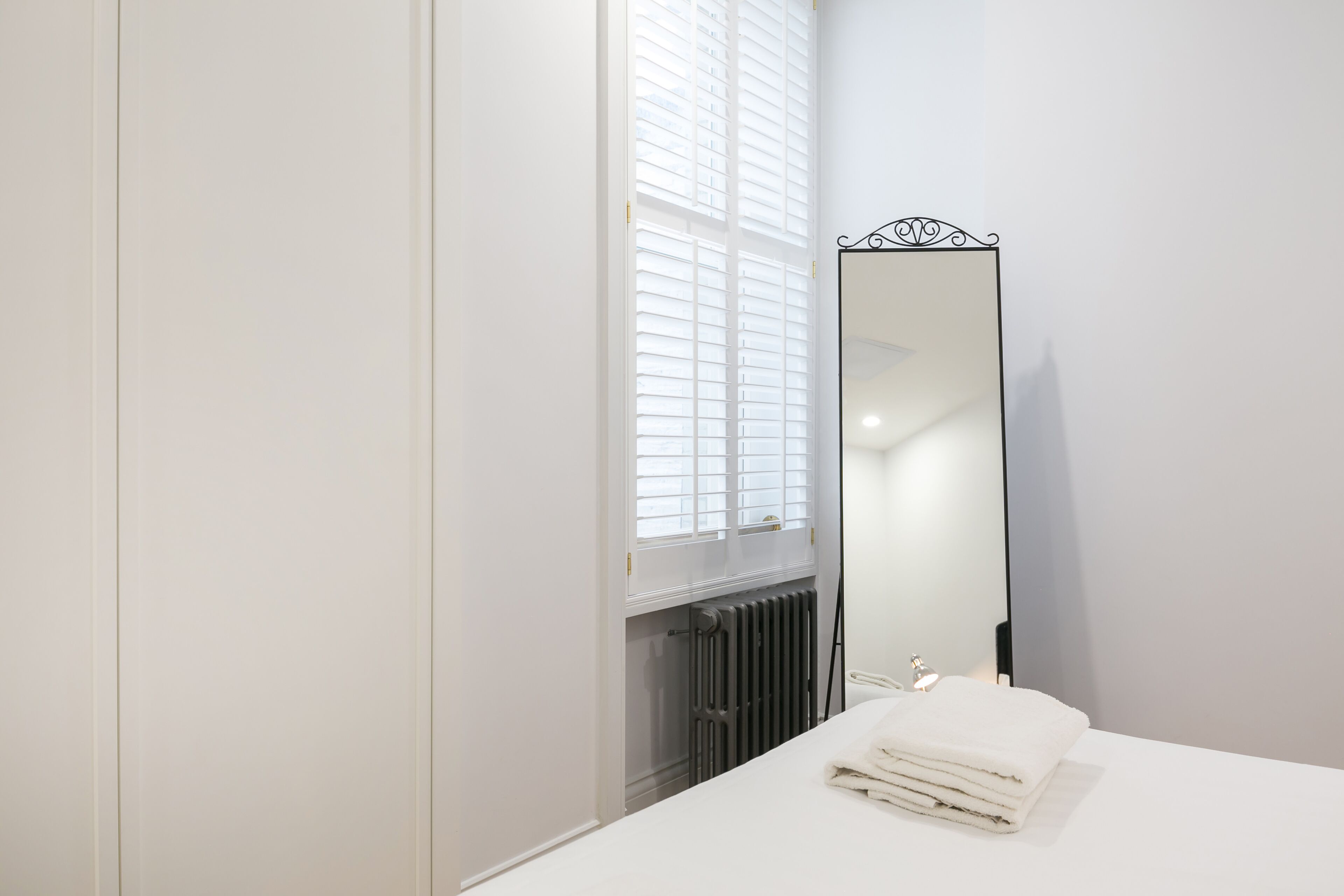A bathroom with a white sink, a mirror, and a radiator.