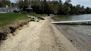 Un chemin de gravier menant à un quai au bord d’un lac, entouré d’arbres et agrémenté d’un belvédère.