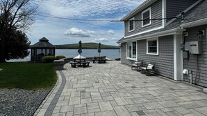 Un espace extérieur aménagé avec un sol en pierre, des sièges et une vue sur un lac.