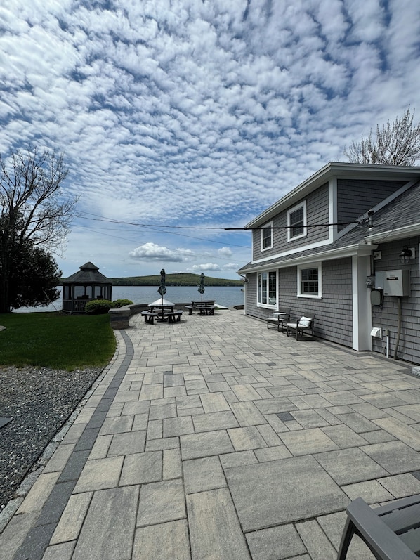 A patio area with stone paving, outdoor seating, and a view of a lake.