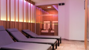 Ein Spa-Raum mit mehreren Massageliegen und einem sichtbaren Sauna-Bereich.