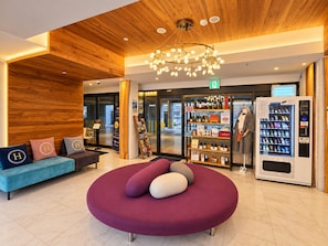 A modern lobby with a wooden ceiling, a round seating area, a vending machine, and a display of bottled beverages. - Hound Hotel Busan Station (Busan)