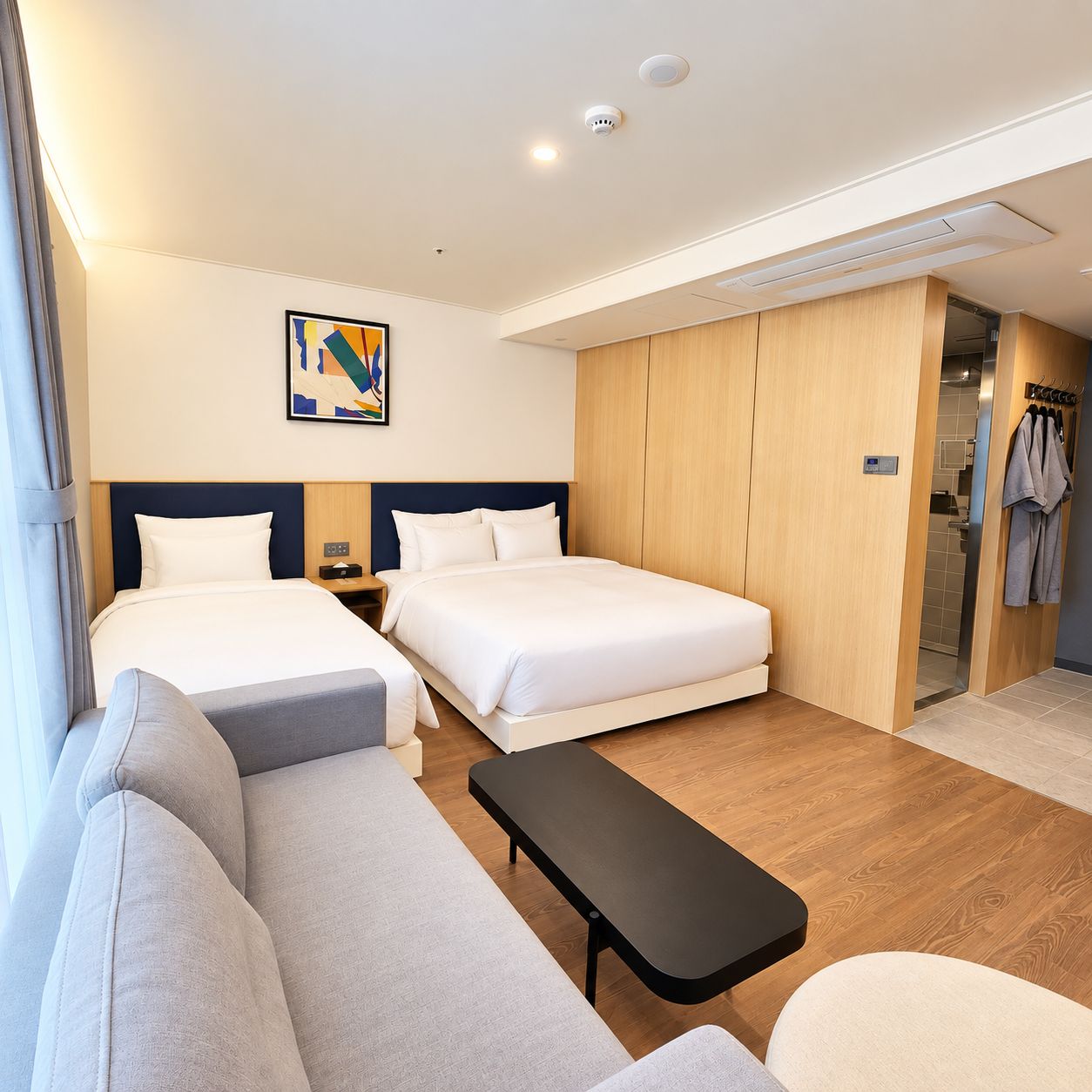 A hotel room with two beds, a sofa, a small table, and a painting on the wall.