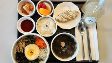 A tray with various food items including rice, soup, and a grilled chicken piece.