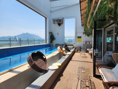 Una piscina al aire libre, sombrillas, sillones reclinables de piscina