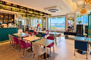 Un restaurante moderno con barra, asientos coloridos y vistas a la ciudad.