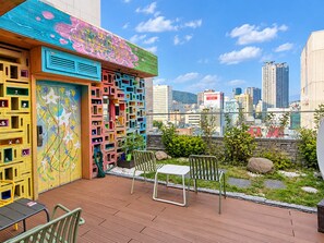 Un balcón con vista a la ciudad, contenedores de almacenamiento de colores y mobiliario exterior.