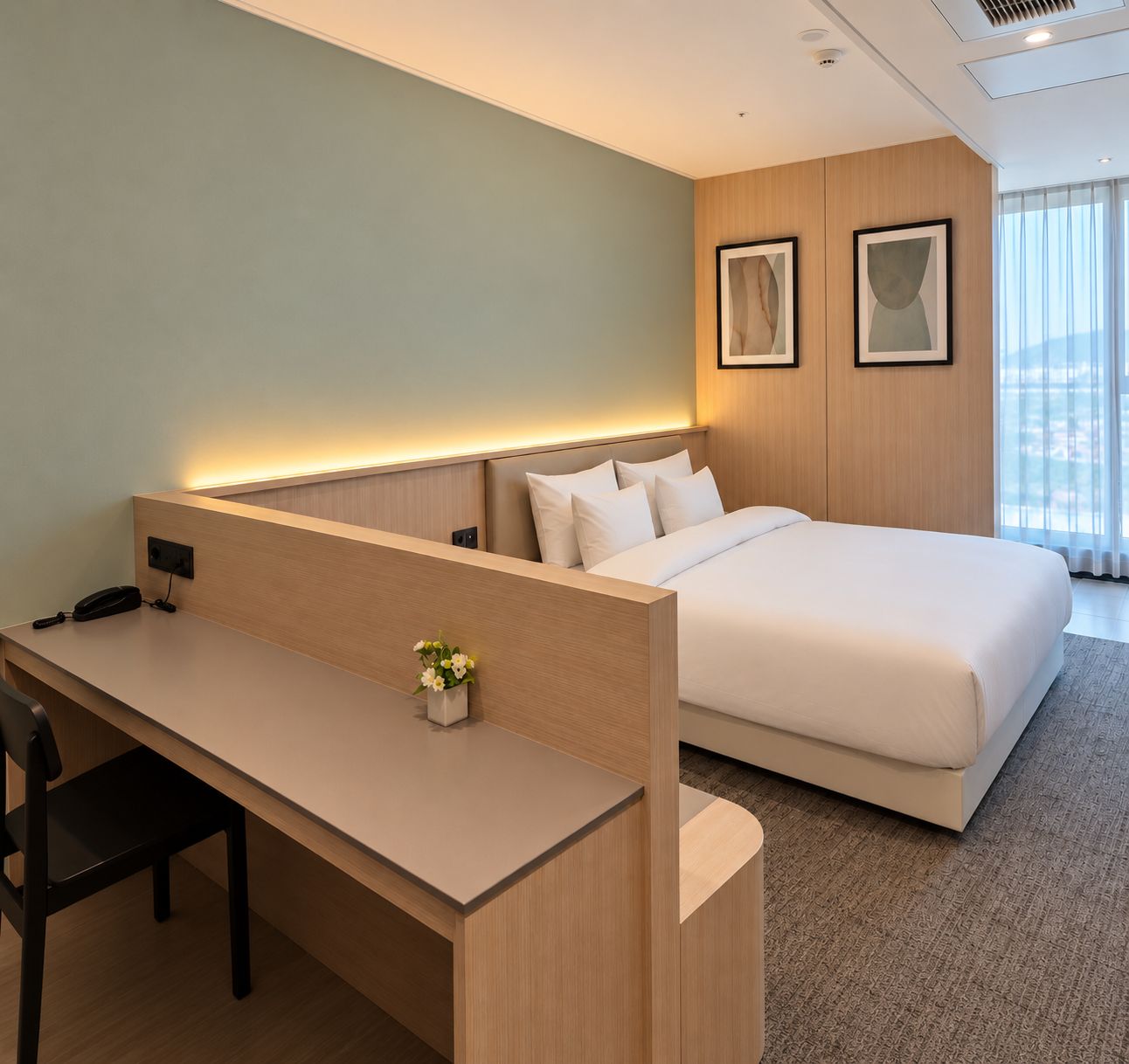Une chambre d’hôtel avec un bureau, un lit et deux tableaux encadrés au mur.