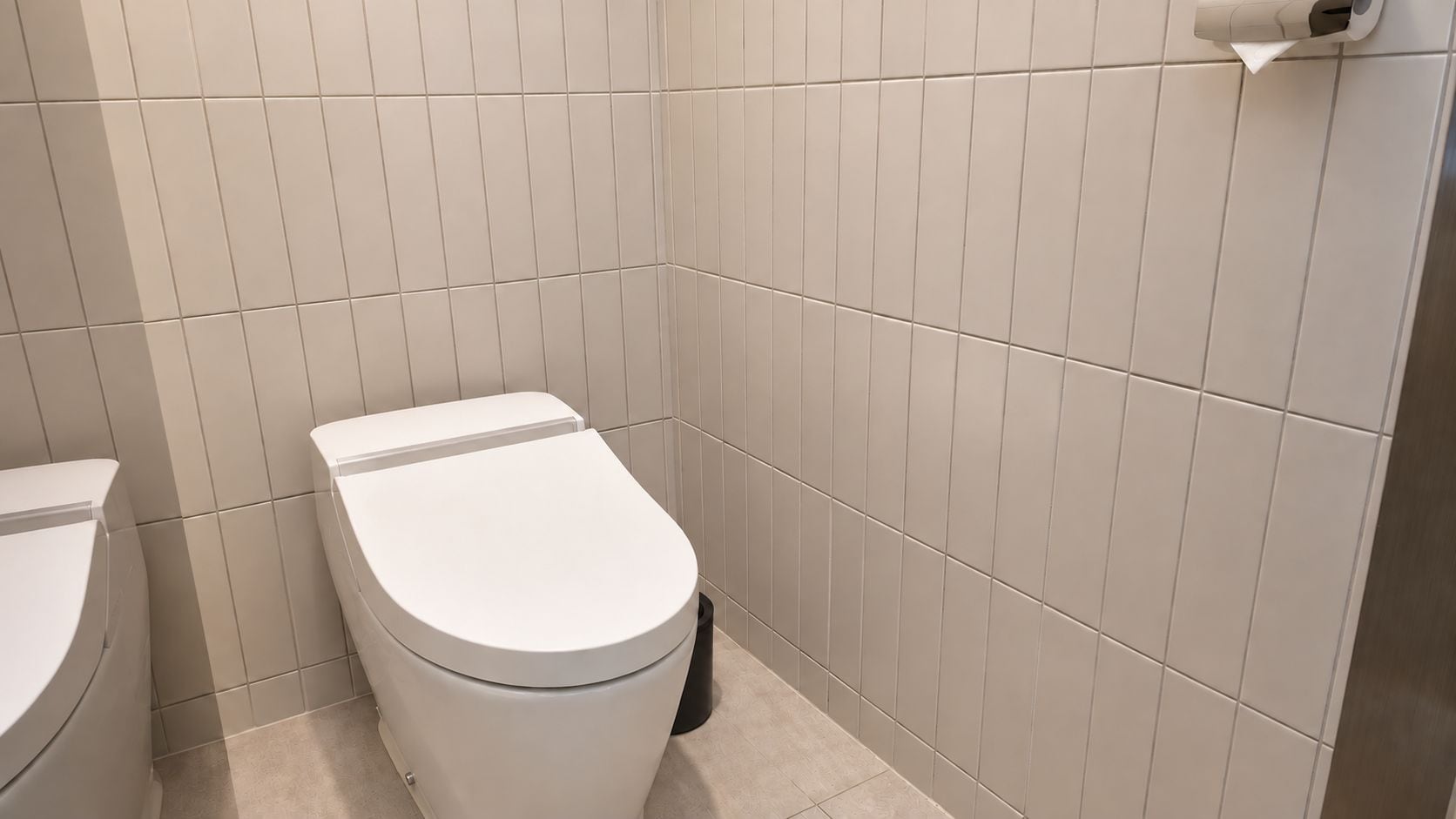 Ein Badezimmer mit Toilette und Bidet, beides weiß, vor einer gefliesten Wand.