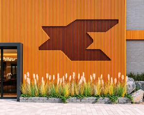 A building facade with vertical wooden slats and a large arrow-shaped cutout. - Hound Hotel Busan Station (Busan)