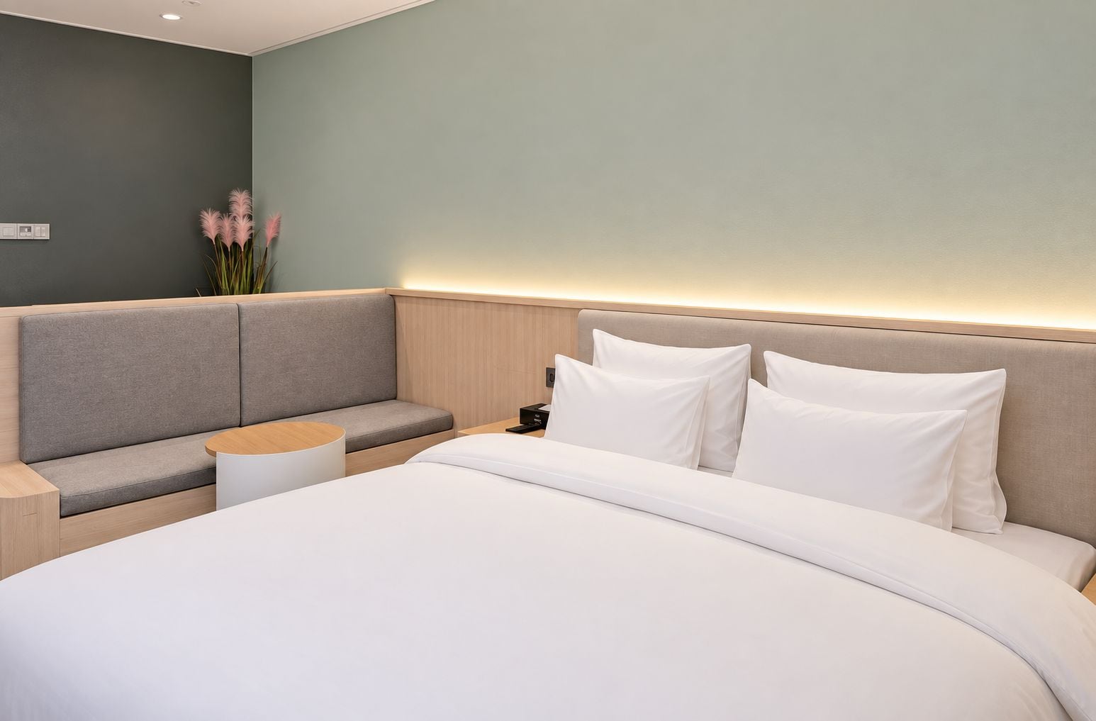 A modern hotel room with a large bed, a seating area, and a nightstand.