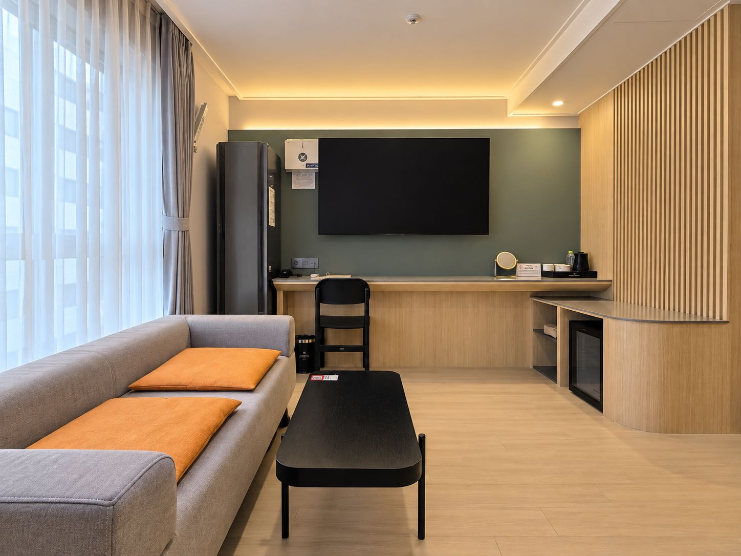 A modern living room with a sofa, a coffee table, and a desk area with a flat-screen TV.