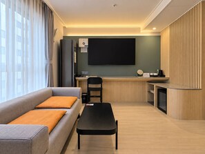 A modern living room with a sofa, a coffee table, and a desk area with a flat-screen TV. - Hound Hotel Busan Station (Busan)