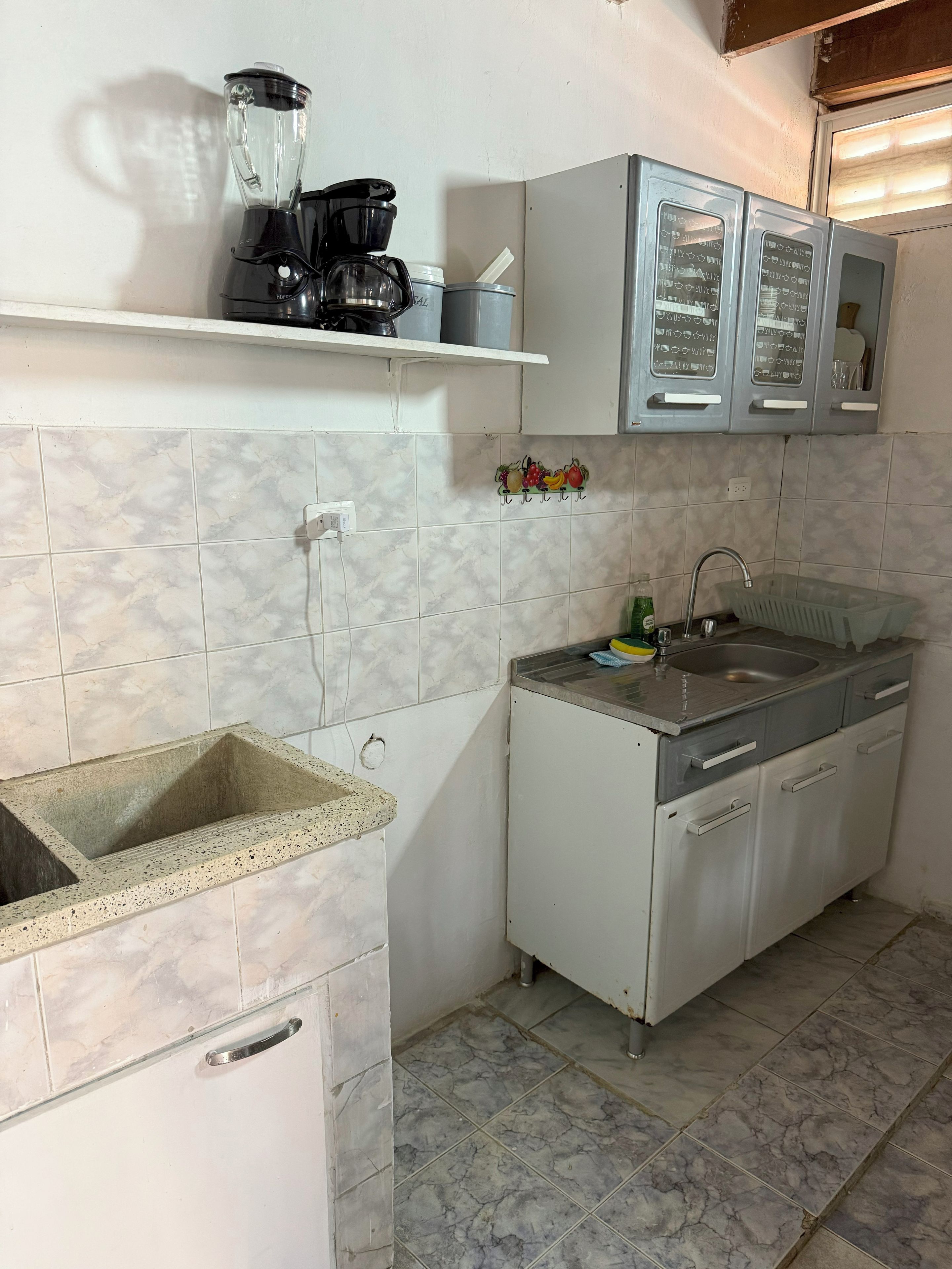 Cocina pequeña con lavamanos, encimera, cafetera y armarios.