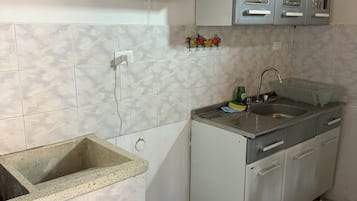 Cocina pequeña con lavamanos, encimera, cafetera y armarios.