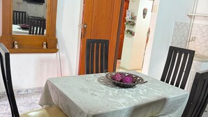 Uma sala de jantar com uma mesa posta para quatro pessoas, uma porta de madeira com o número 202 e um espelho refletindo o ambiente.