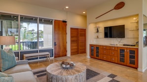 A modern kitchen with a large TV, wooden cabinets, and a dining area with a bench.