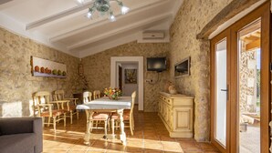 A dining area with a wooden table and chairs, a sofa, and a TV mounted on the wall. - Beautiful farm with 2 bedrooms, 2 bathrooms, wifi, pool and barbecue (Caimari)