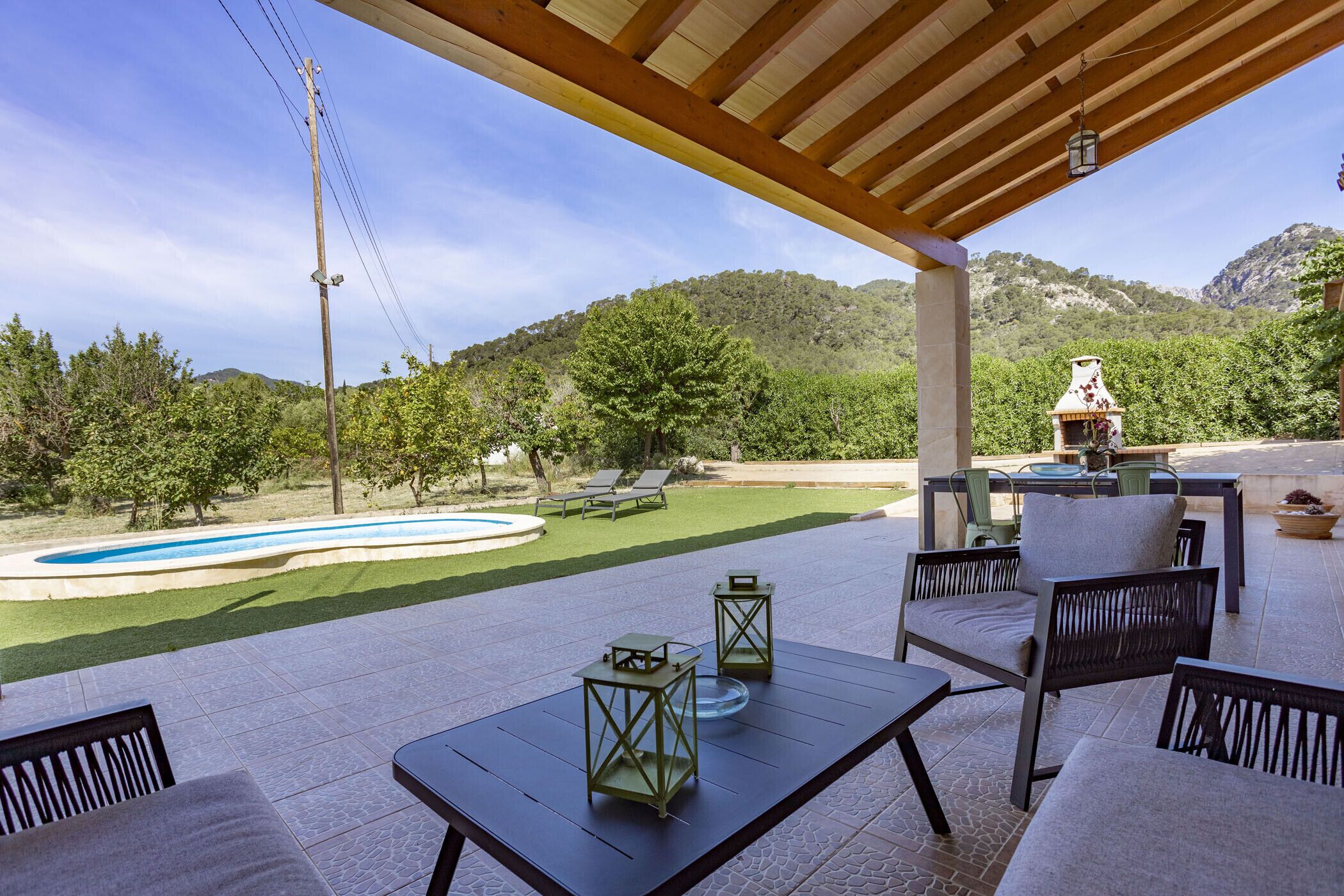 An outdoor patio with a pool, lounge chairs, and a barbecue area.