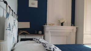 A bedroom with a bed, a bedside table, a lamp, a fireplace, and a wall with a picture. - Character house for up to 6 people (Telgruc-sur-Mer)