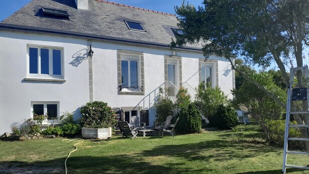 A two-story house with a white exterior, a tiled roof, and a small garden area with a lawn and potted plants. - Character house for up to 6 people (Telgruc-sur-Mer)