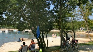 Un parque junto al lago con playa de arena, árboles y bicicletas.