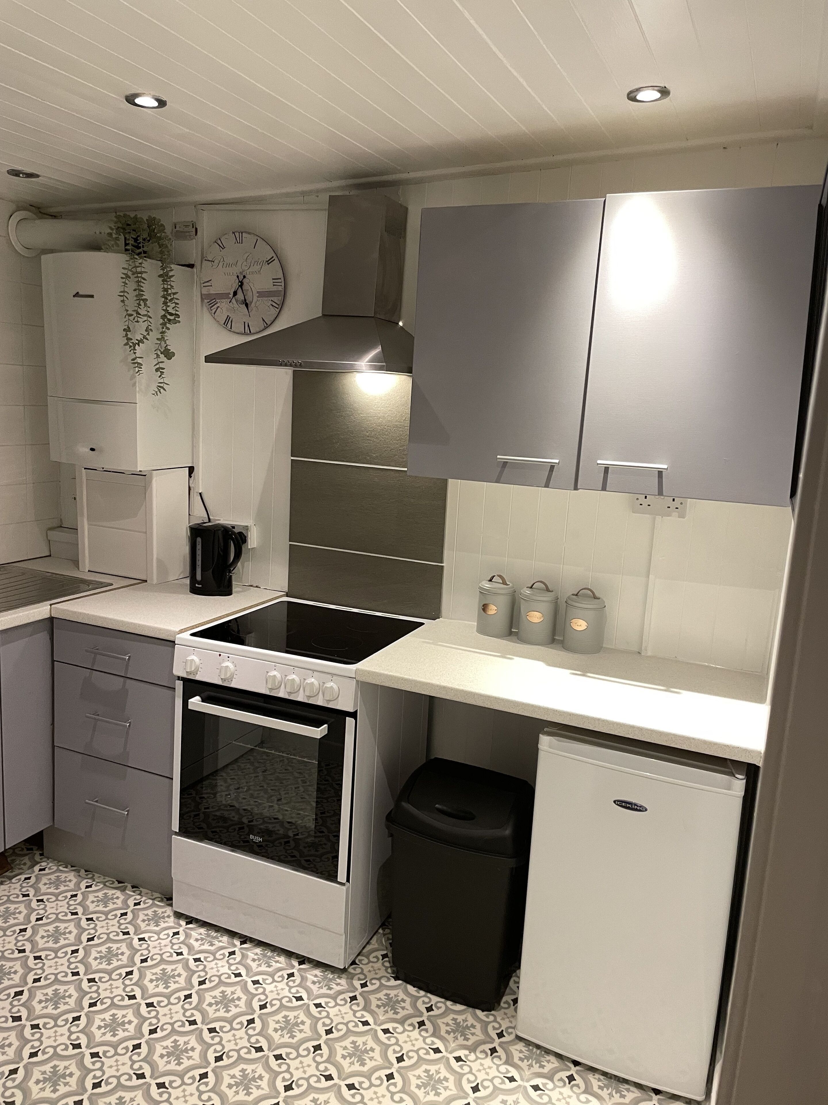 A compact kitchen with white cabinets, a stove, oven, and a small refrigerator.