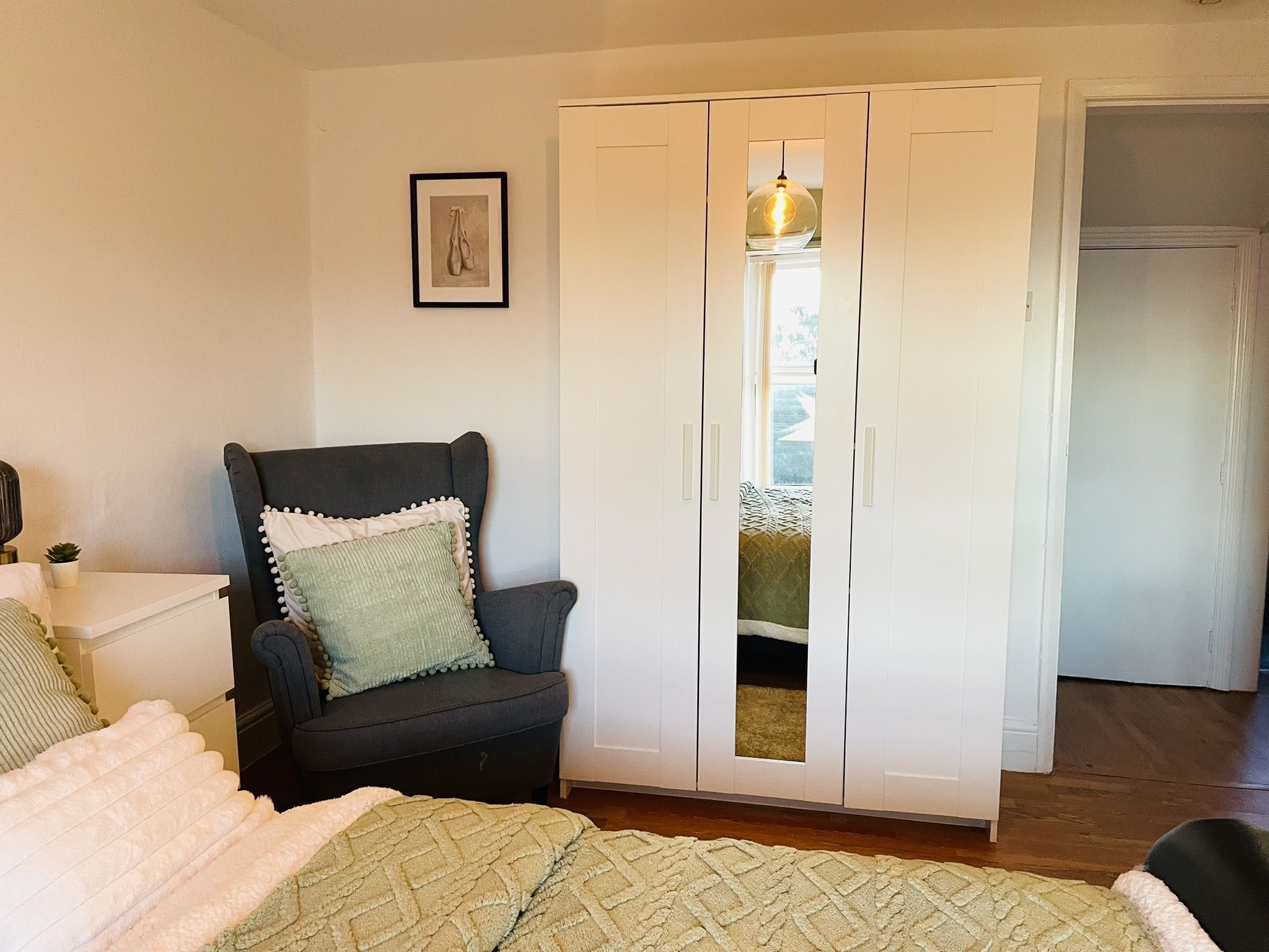 Une chambre à coucher avec un lit, une chaise, une armoire et une fenêtre.