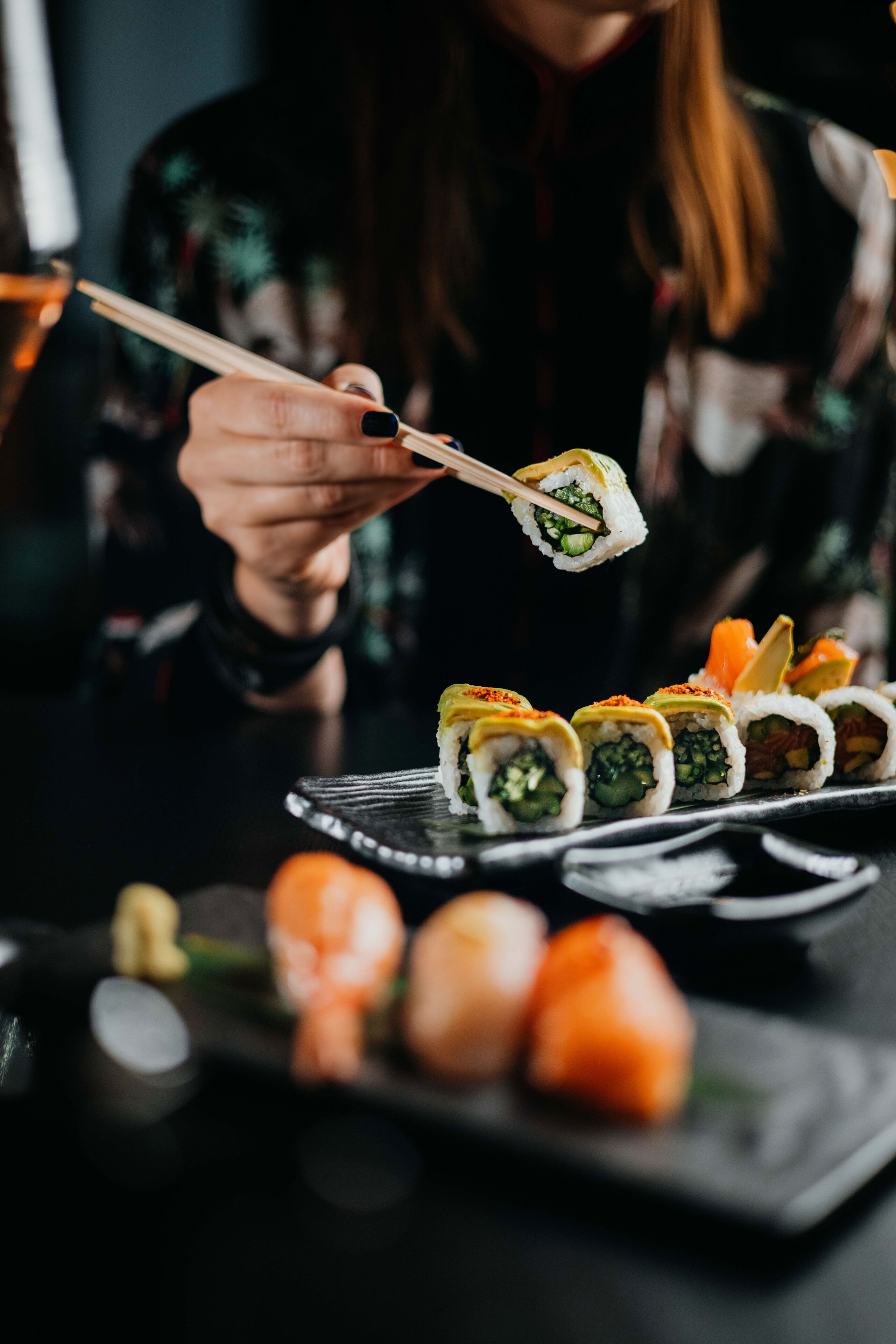 A person holding sushi with chopsticks.