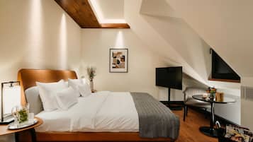 Una camera d'albergo moderna con un grande letto, un comodino con una lampada, un tavolino con un vaso, un quadro appeso alla parete e un televisore su un mobile.