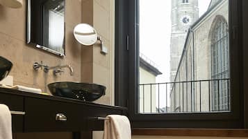 A bathroom with a large window, a sink with a basin, a mirror, and a towel rack.