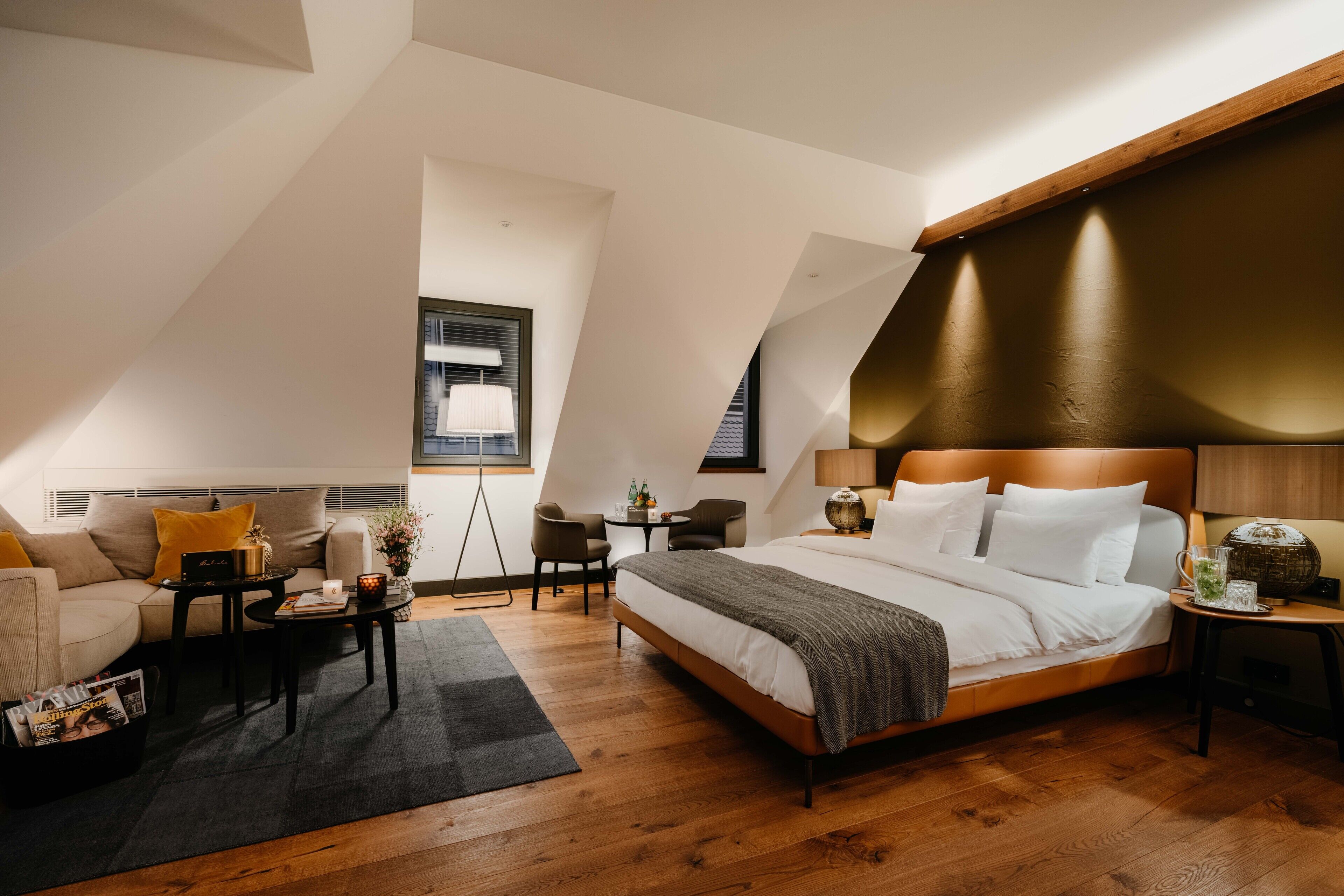 Un dormitorio moderno con una cama grande, un sofá, una mesita y una silla.