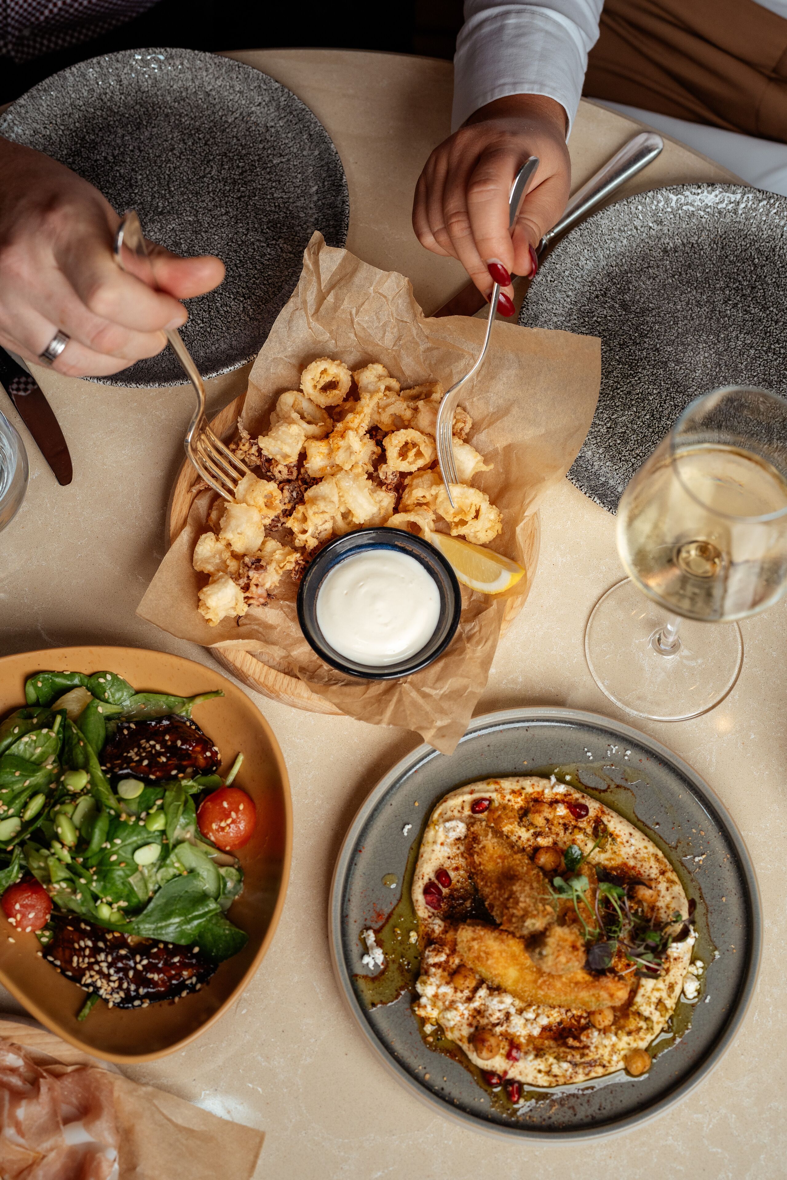 A table with a variety of dishes including a salad, a plate with a fish dish, and a basket of fried items.