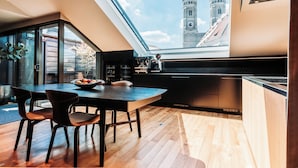 A modern kitchen with a skylight, wooden flooring, and a view of a tower. - DO & CO Hotel München (Munich)