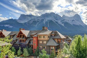 A lodge with multiple buildings, each featuring a sloped roof and wooden construction, set against a backdrop of mountains. - Sun Drenched Escape (Canmore)