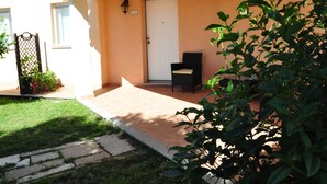 A house with a white door, a small porch, and a garden. - Sa Teria Village - apartment 2 (tertenia)