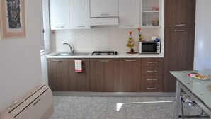 A modern kitchen with white and dark wood cabinets, a microwave, and a tiled backsplash. - Sa Teria Village - apartment 2 (tertenia)