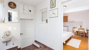 Une chambre à coucher avec un lit, un petit bureau et une chaise. Il y a une fenêtre et une porte.