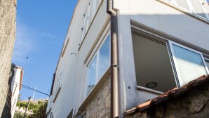 Un bâtiment à deux étages, doté d’une façade en pierre, d’une rambarde métallique à l’étage supérieur et d’une porte bien visible au rez-de-chaussée.