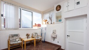 Une petite pièce bien éclairée, avec deux chaises, une table et une porte blanche.