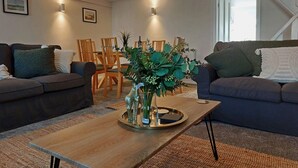 Un salon comprenant une table basse en bois, deux canapés, une table à manger avec des chaises et un éclairage fixé au mur.