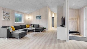 A modern living room with a grey sectional sofa, a small round coffee table, and a TV on a stand.