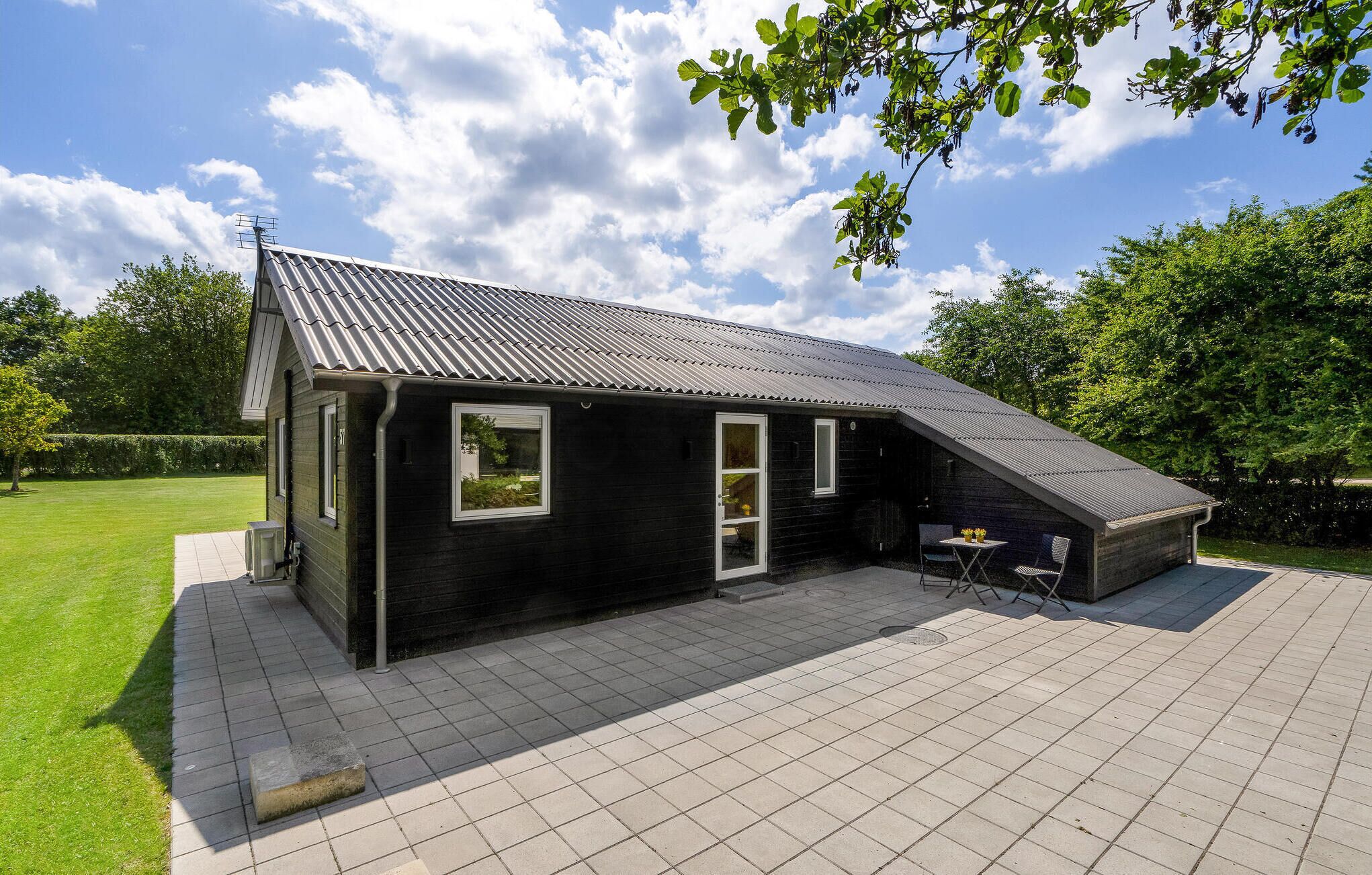 A black metal-roofed building with a small patio area, a window, and a door.