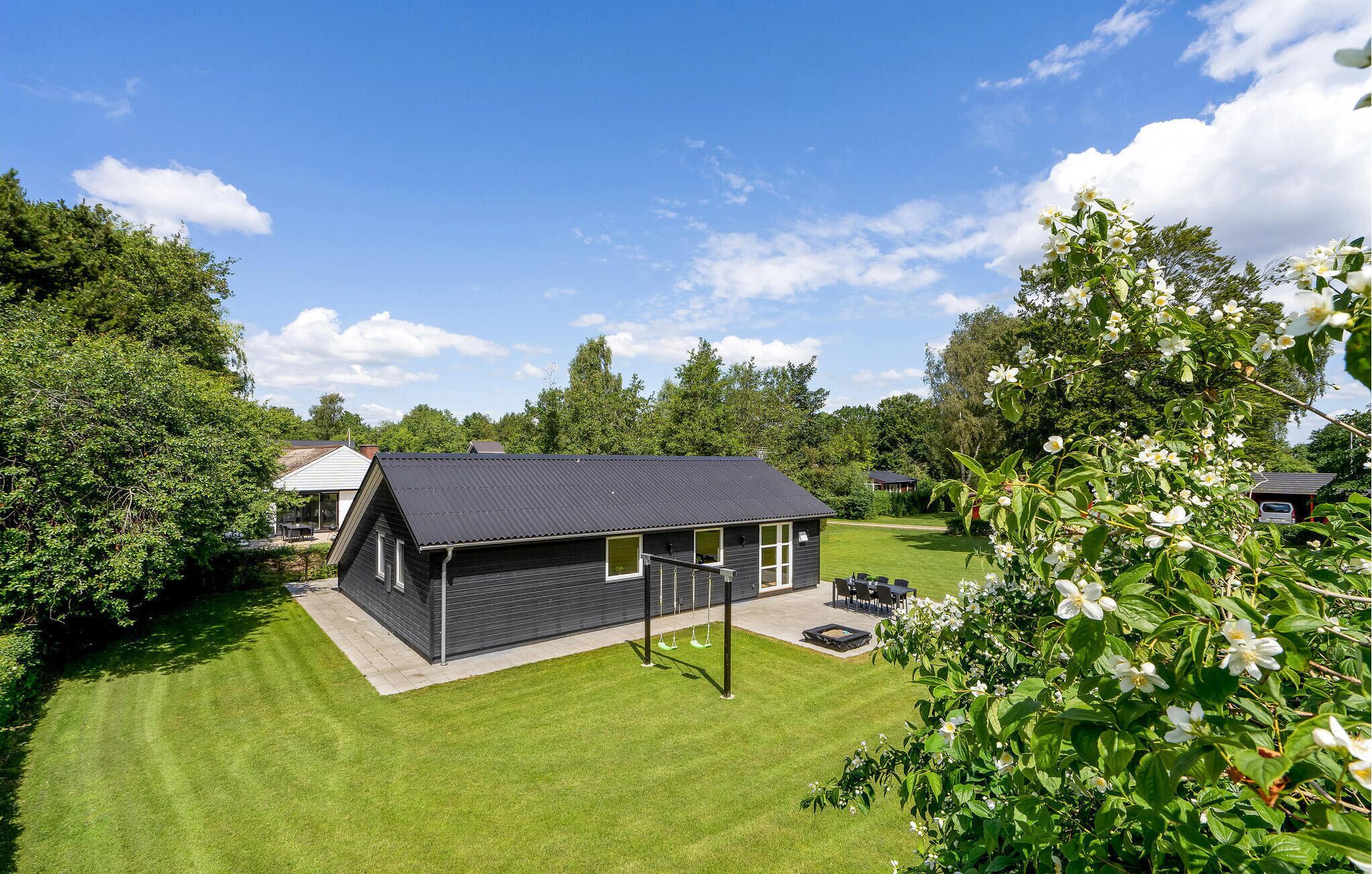A modern house with a dark roof, a covered patio, and a well-maintained lawn.