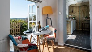A dining area with a table and chairs, a lamp, and a view of the countryside.