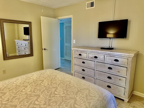 Un dormitorio con cama, cómoda, espejo y televisor.