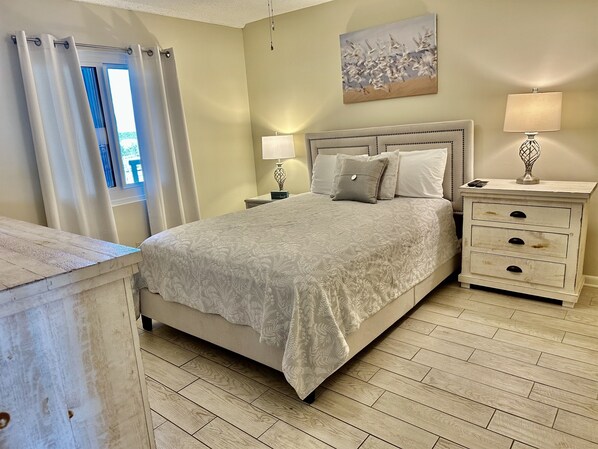 A bedroom with a bed, nightstands, a dresser, and a painting on the wall. - 3 Bedroom Beach Front Condo at Romar Towers with Amazing Views on the 8th Floor! (Orange Beach)