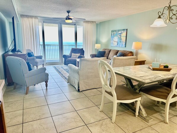 A living room with a dining table, striped chairs, a sofa, and a ceiling fan. - 3 Bedroom Beach Front Condo at Romar Towers with Amazing Views on the 8th Floor! (Orange Beach)