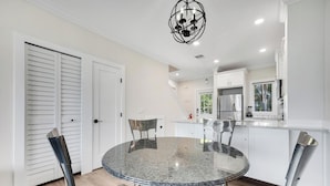 Een moderne keuken met witte kastjes, een roestvrijstalen koelkast en een glazen eettafel met metalen stoelen.