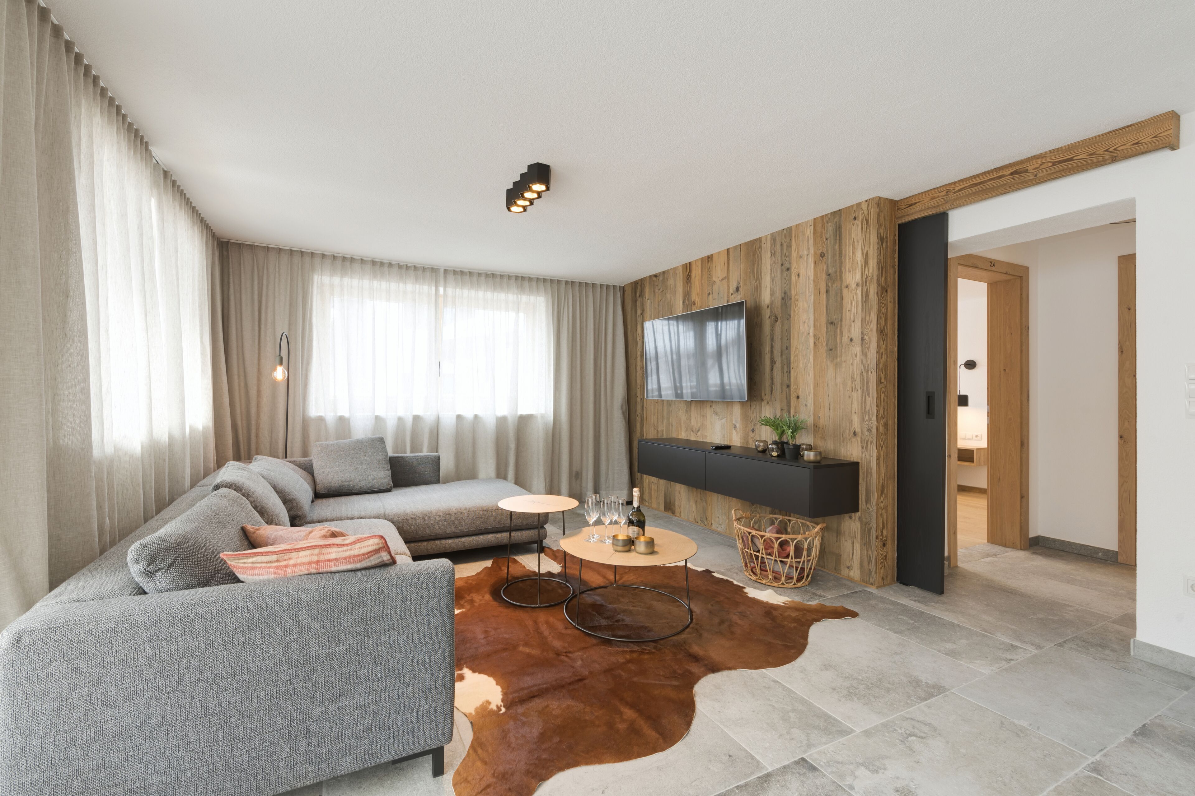 A modern living room with a sofa, a coffee table, and a TV mounted on a wooden wall.